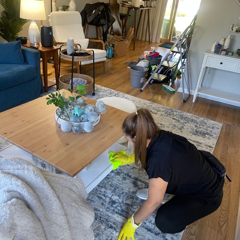 Cleaner detailing a wooden coffee table in a bright living room